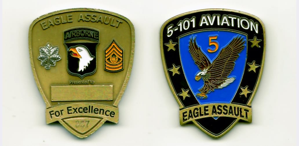 Shield shaped with banner across base of shield, brass colored coin 1-1/2 inches wide x 2 inches high.