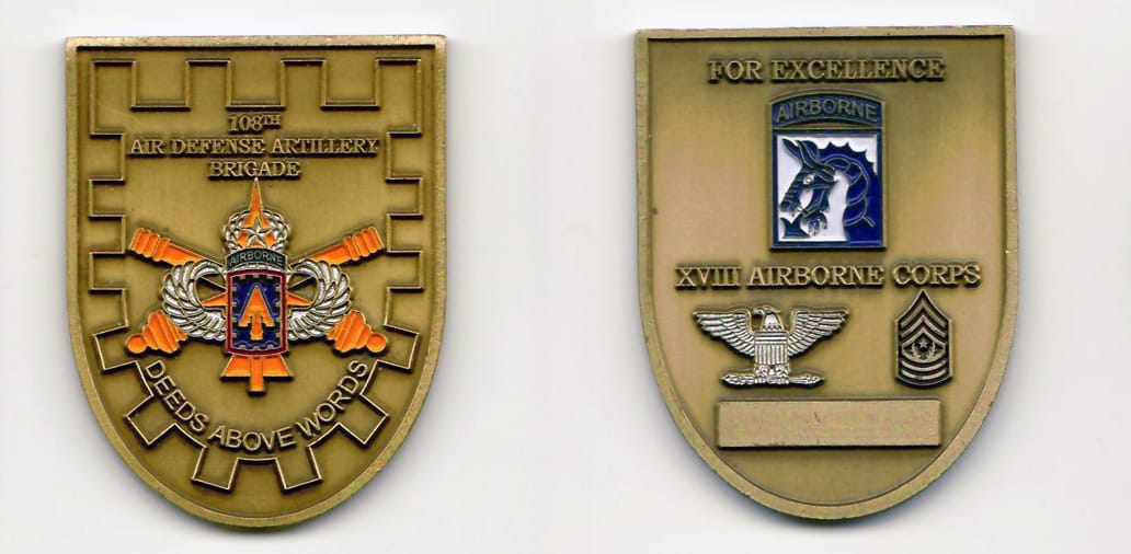 Shield shaped with a rounded bottom, brass colored coin 1-7/8 inches wide x 2-1/3 inches high