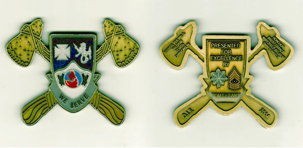 Shield with cross hatchets protruding from behind shaped, antique brass colored coin 2-3/4 inches wide x 2-1/8 inches hi...