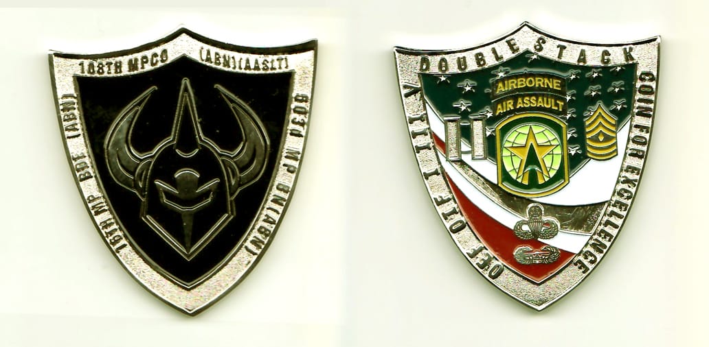 Shield shaped, silver colored coin, 1-7/8 inches high x 1-3/4 inches wide.