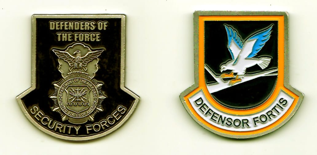 Shield shaped with banner on bottom, silver colored coin, 1-3/4 inches high x 1-1/4 inches wide.