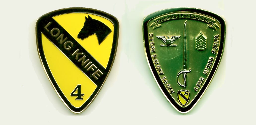 Shield shaped, gold colored coin, with rounded top, 3 inches high x 2-1/4 inches wide.