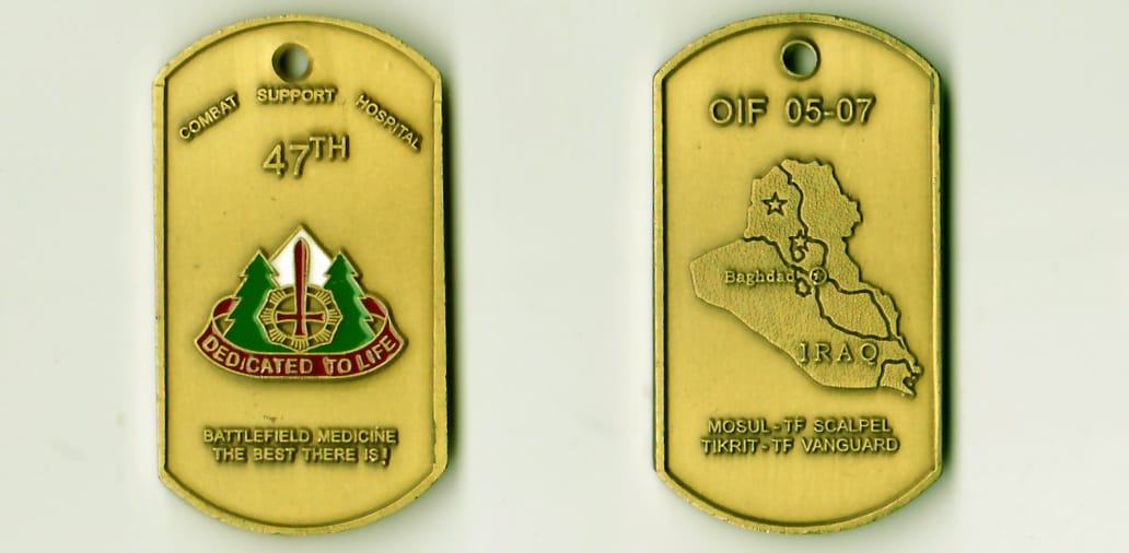 Dog tag shaped, antique gold colored coin, 1-3/16 inches high x 2-1/8 inches wide.