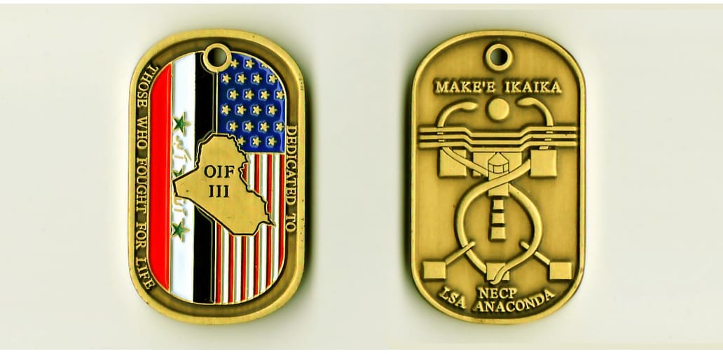 Dog tag shaped, light gold colored coin, 1-3/4 inch high x 1 inch wide.