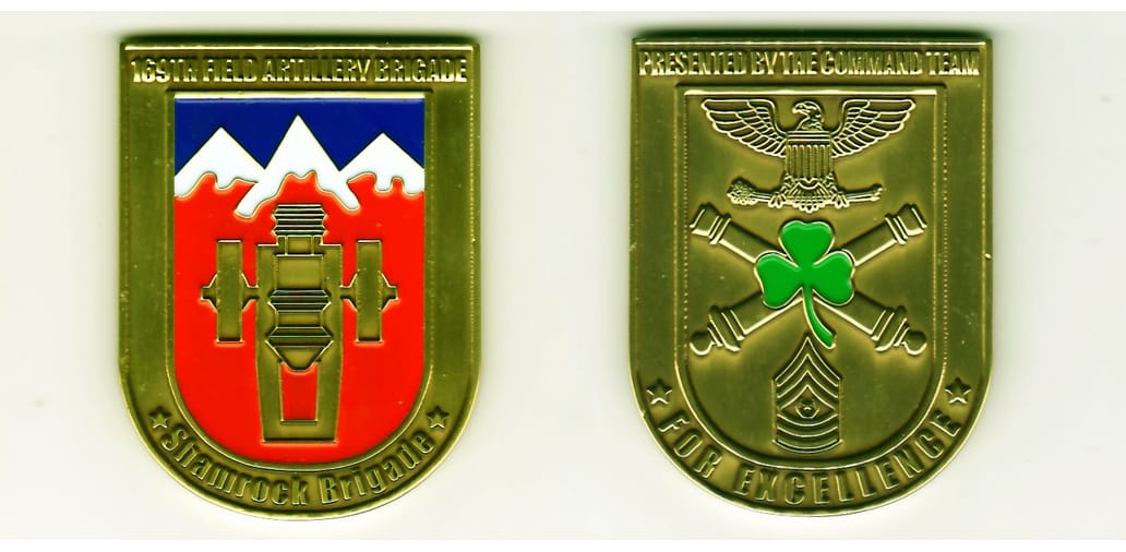 Shield shaped with rounded bottom, brass colored coin, 1-7/8 inches high x 1-1/2 inches wide.