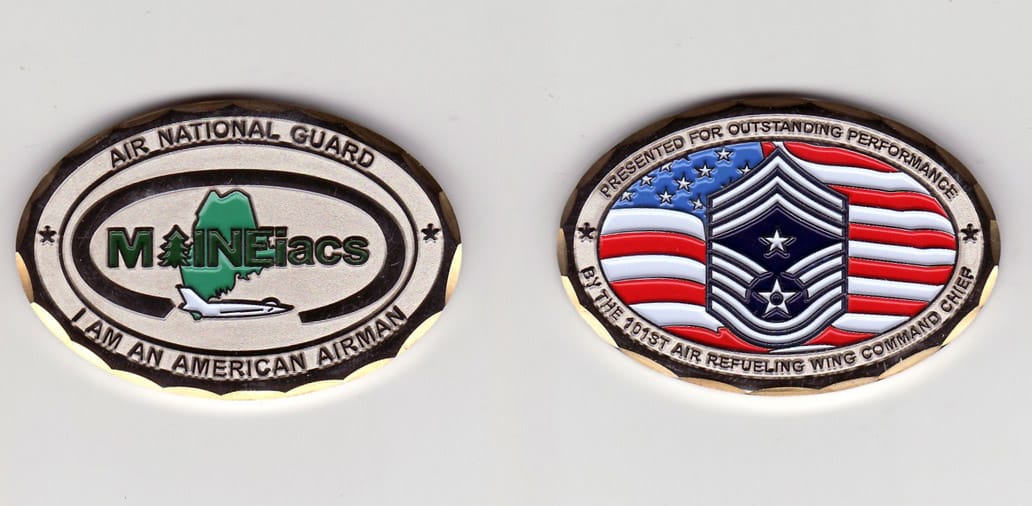 Oval shaped, silver colored coin with gold colored rim, 2- 1/4 inches wide x 1- 1/2 inches high.