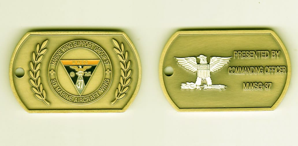 Dog tag shaped, antique brass colored coin, 2 inches wide x 1 inch high.