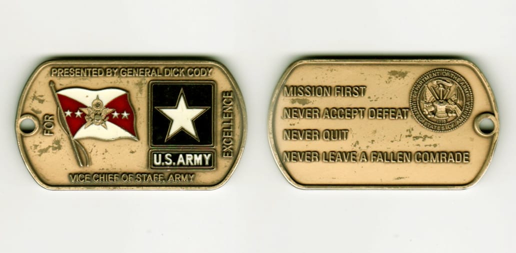 Dog tag shaped, antique brass colored coin, 2-1/4 inches wide x 1 inch high.