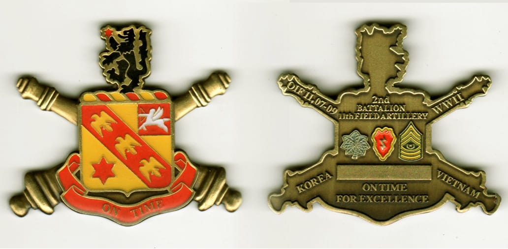 Shield shaped with extended artillery cannons, brushed brass colored coin, 2  inches wide x 2 inches high.