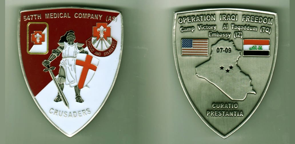 Shield shaped, brass colored coin, 2 inches wide x 2 3/4 inches high.