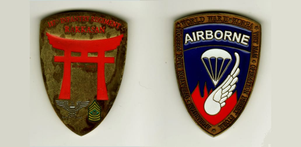 Shield shaped, brass colored coin, 1 3/4 inches wide x 2 inches high.