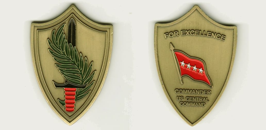 Shield shaped, brass colored coin, 1 3/4 inches wide x 2 1/2 inches high.