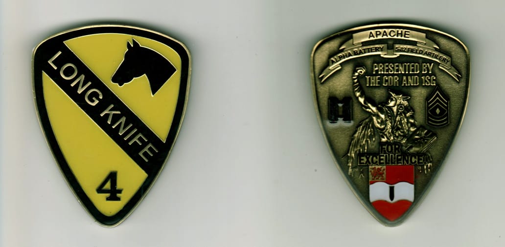 Shield shaped, brass colored coin, 2 inches wide x 2 1/4 inches high.