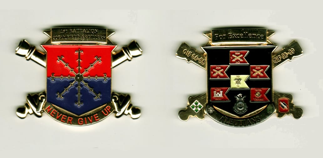 Shield shaped with crossed artillery canons extended on sides, gold colored coin, 1 1/2 inches wide x 1 3/4 inches high.