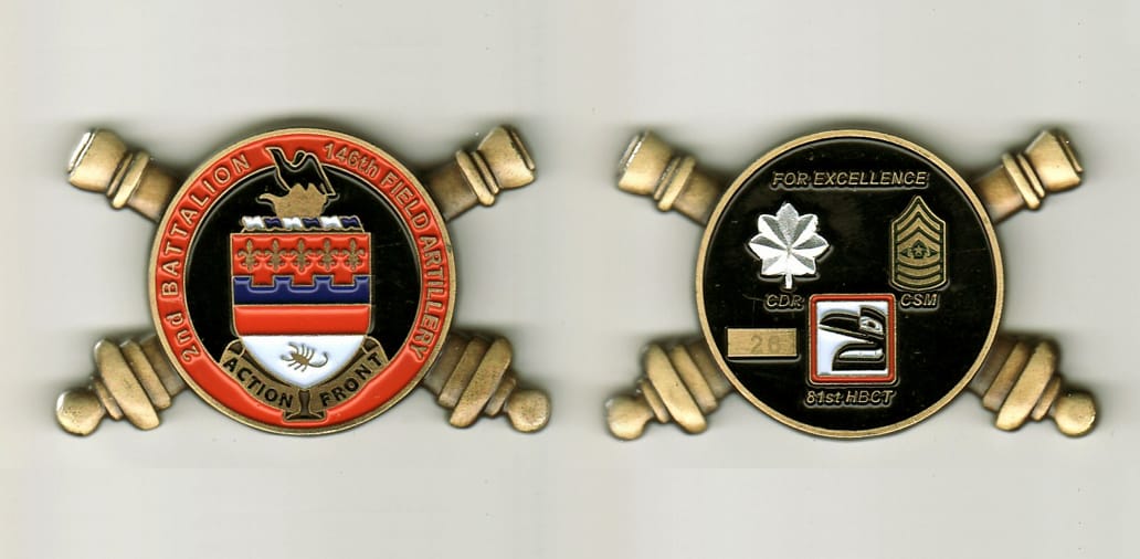 Round shaped with crossed artillery canons extended on sides, brass colored coin, 2 inches wide x 1 1/4 inches high.