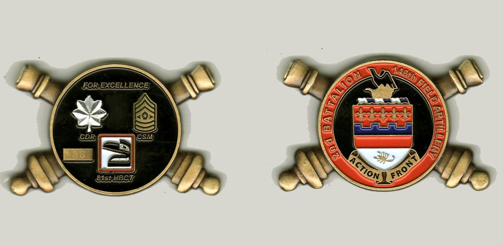 Round shaped with crossed artillery canons extended on sides, brass colored coin, 2 inches wide x 1 1/4 inches high.