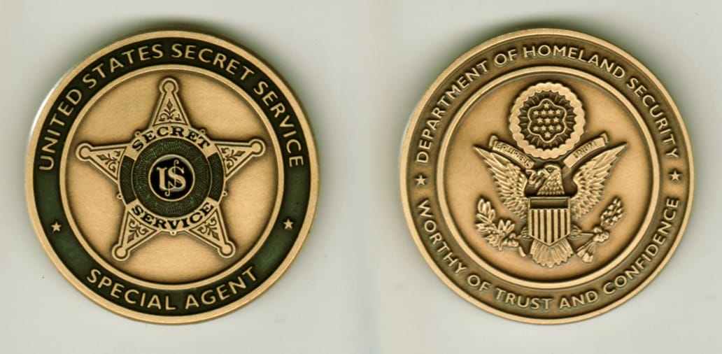 Round shaped, brass colored coin, 1 13/16 inches in diameter.