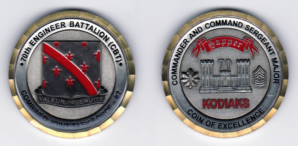 Round shaped, pewter colored coin with gold colored rim, 2 inches in diameter.