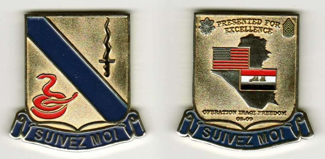 Squared off-shield shaped, gold colored coin, with attached banner beneath, 1-1/2 inches wide x 2 inches high.