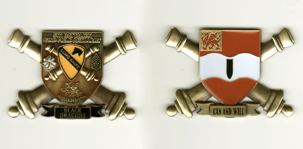 Shield  shaped with crossed cannons extending and banner below, brass colored coin, 1 1/2 inches high x 2 1/2  inches wi...