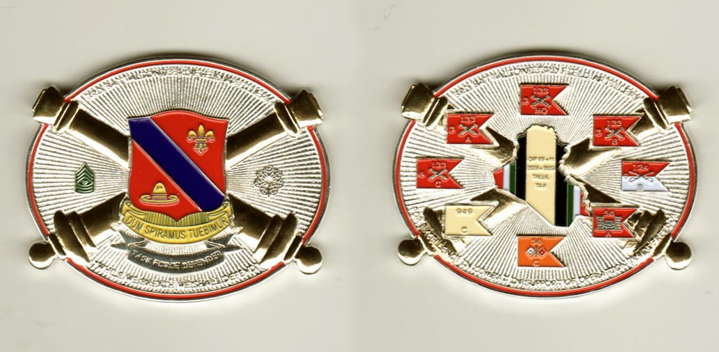 Oval shaped, silver colored coin with ends of crossed cannons extending, 2  inches high x 2 1/2 inches wide.