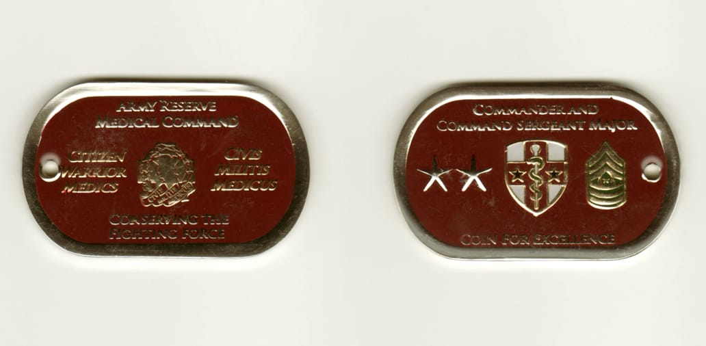 Dog Tag shaped, silver colored coin, 1 inch high x 1 3/4 inches wide.