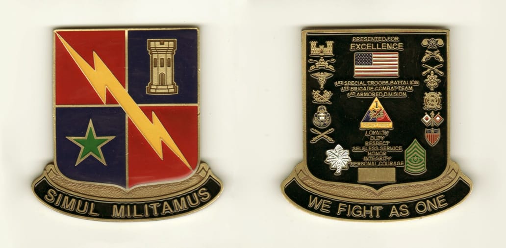 Shield shaped with banner mounted below, brass colored coin, 2  3/4 inches high x 2 inches wide.