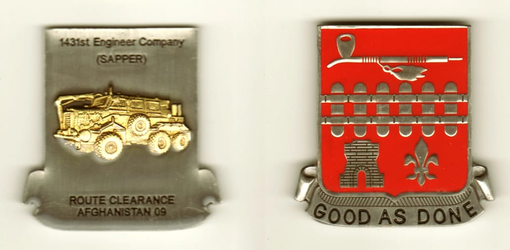 Shield shaped with banner mounted below, pewter colored coin, 2  1/8 inches high x 1 3/4 inches wide.