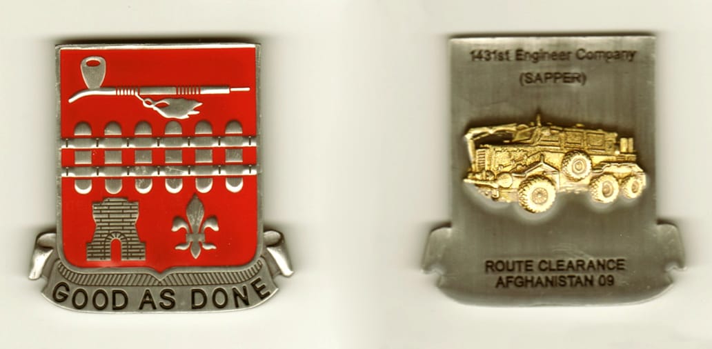 Shield shaped with banner mounted below, pewter colored coin, 2  1/8 inches high x 1 3/4 inches wide.