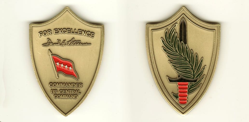 Shield shaped, brass colored coin, 1 3/4 inches wide x 2 1/2 inches high.