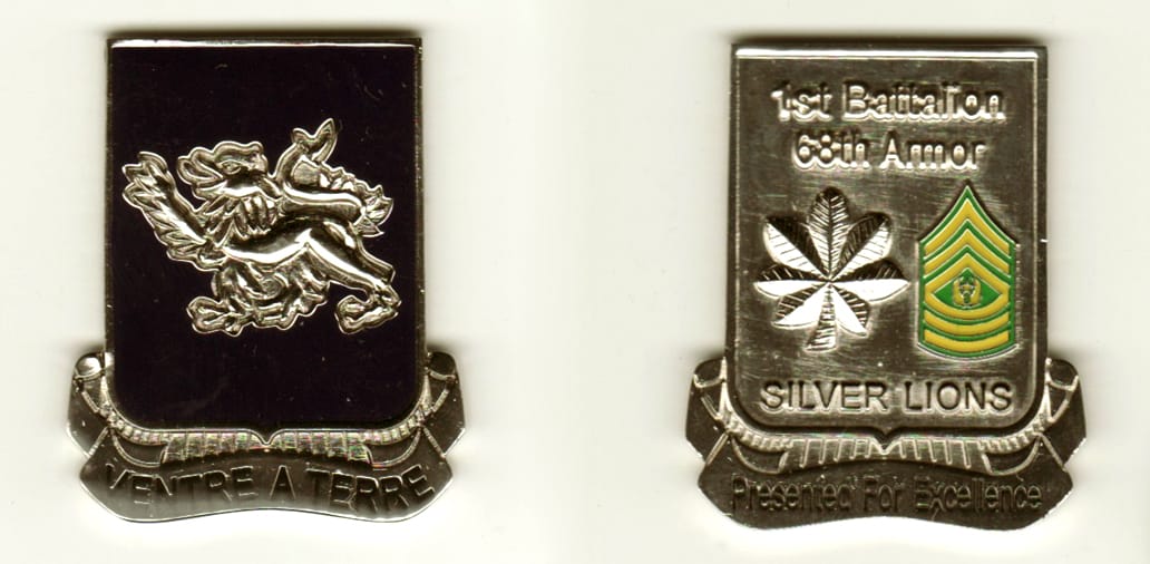 Shield shaped, with banner mounted below, silver colored coin, 1 1/8 inches wide x 1 1/2 inches high.