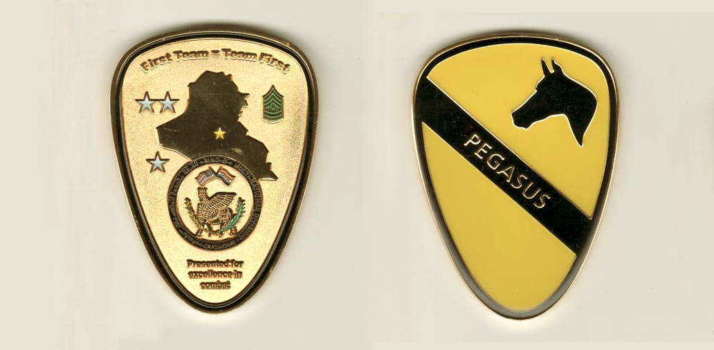 Shield shaped, gold colored coin, with rounded top, 3 inches high x 2-1/4 inches wide.