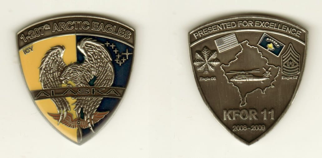 Shield shaped, pewter colored coin, 2 inches wide x 1 1/2 inches high