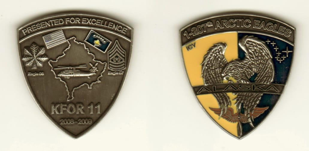 Shield shaped, pewter colored coin, 2 inches wide x 1 1/2 inches high