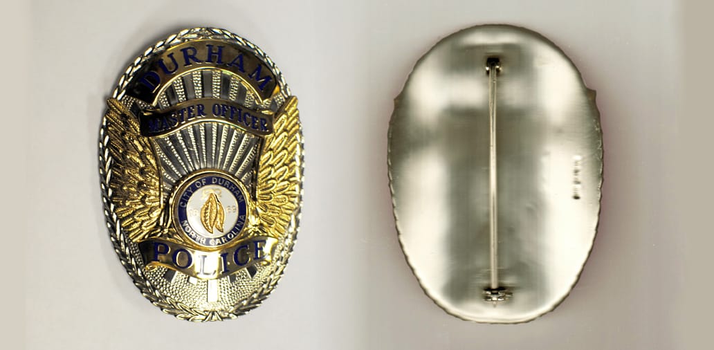 Oval shaped, silver colored badge, 2-1/2 inches wide  by 3-1/4 inches high.