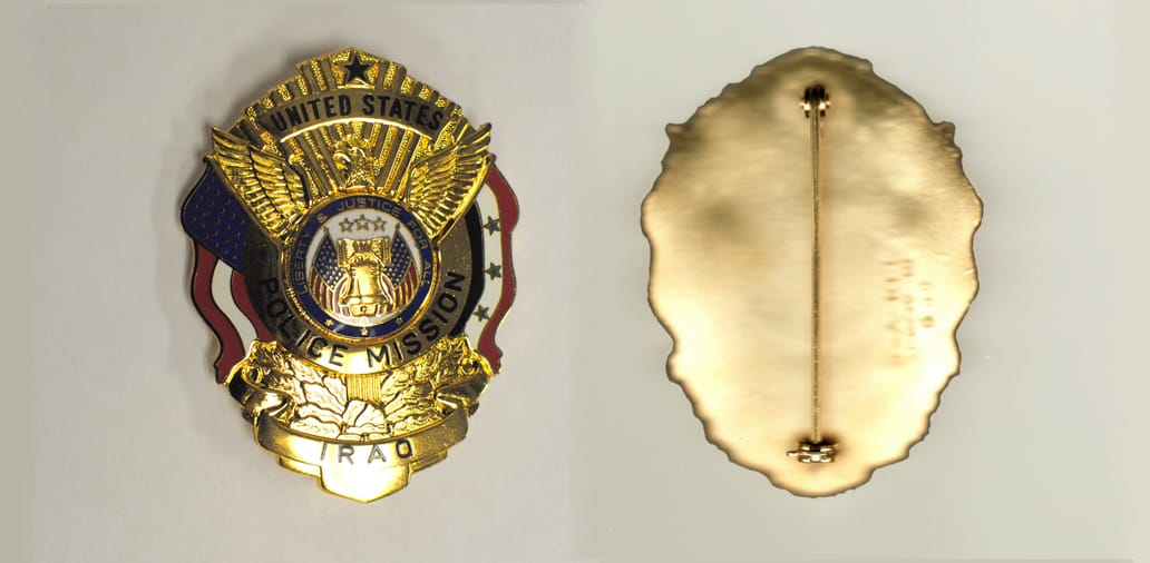 Oval shaped, gold colored badge, 2-1/4 inches wide  by 3 inches high.