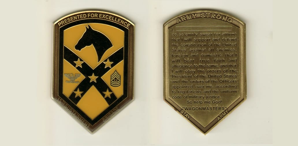 Shield shaped, brass colored coin with rounded top and pointed bottom, 2 inches wide x 3 inches high.