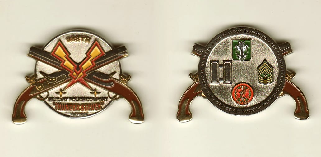 Round shaped, with crossed pistols extended, silver colored coin, 2 inches wide x 1-1/4 inches high.