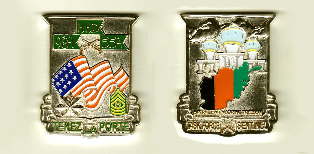 Shield shaped with banner mounted beneath, silver colored coin, 2 inches wide x 2-1/2 inches high.