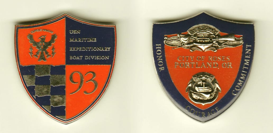 Shield shaped, silver colored coin, 1-3/4 inches wide x 1-7/8 inches high.