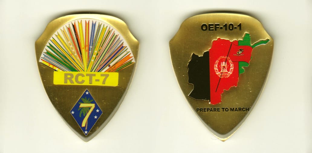 Shield shaped, brass colored coin, 1-5/8 inches wide x 2 inches high.