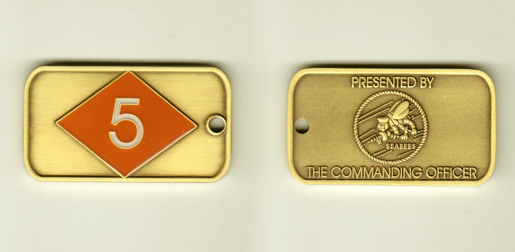Dog tag shaped, brass colored coin, 2-1/4 inches wide x 1-1/4 inches high.