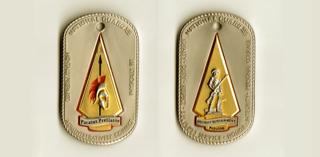 Dog tag shaped, pewter colored coin, 1-1/4 inches wide x 2 inches high.