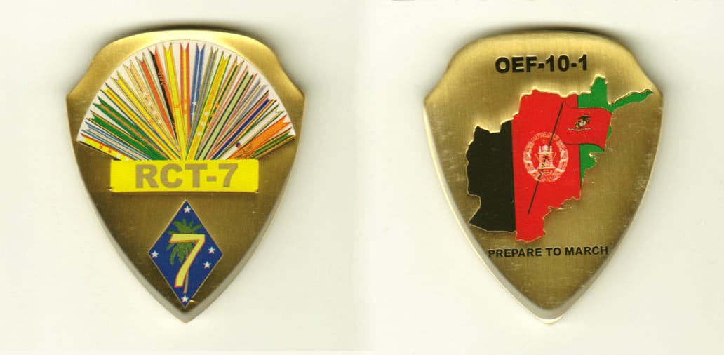 Shield shaped, brass colored coin, 1-5/8 inches wide x 2 inches high.