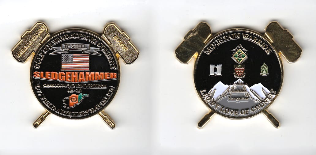 Round shaped, with crossed sledgehammers extended, gold colored coin 2-1/4 inches wide x1-7/8 inches high.