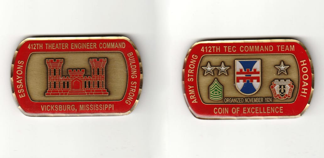 Dog tag shaped, brass colored coin 2-3/4 inches wide x 1-3/4 inches high.