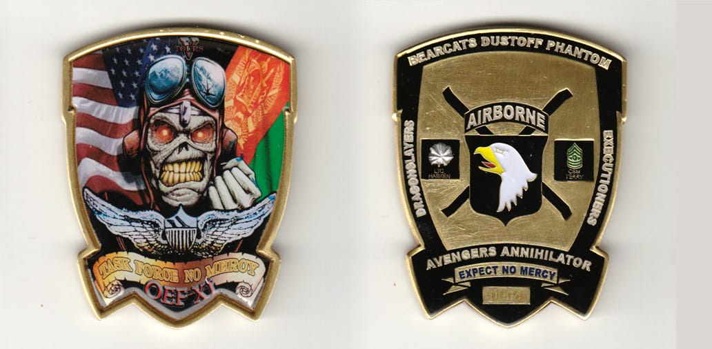 Shield shaped, with banner mounted beneath, brass colored coin 2 inches wide x 2-1/2 inches high.