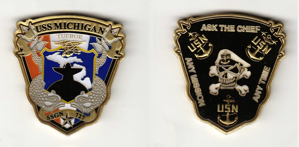 Shield shaped, antique brass colored coin 1-7/8 inches wide x 2 inches high.