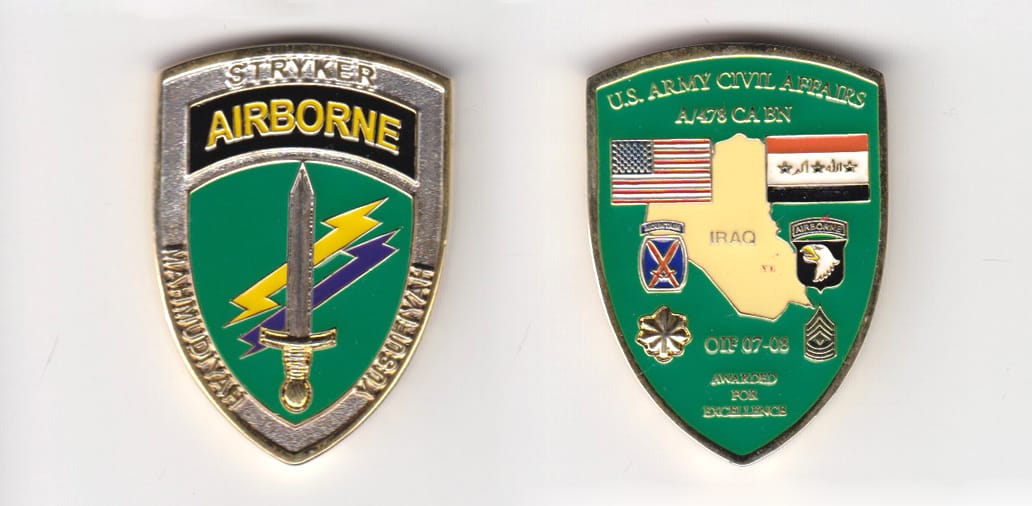 Shield shaped, gold colored coin, 1-1/2 inches wide x 2 inches high.