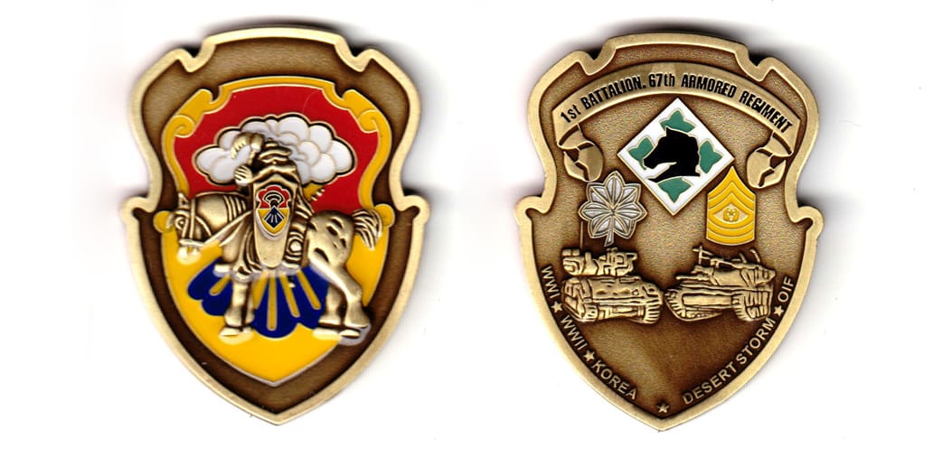 Shield shaped, brass colored coin, 1-3/4 inches wide x 2-1/4 inches high.